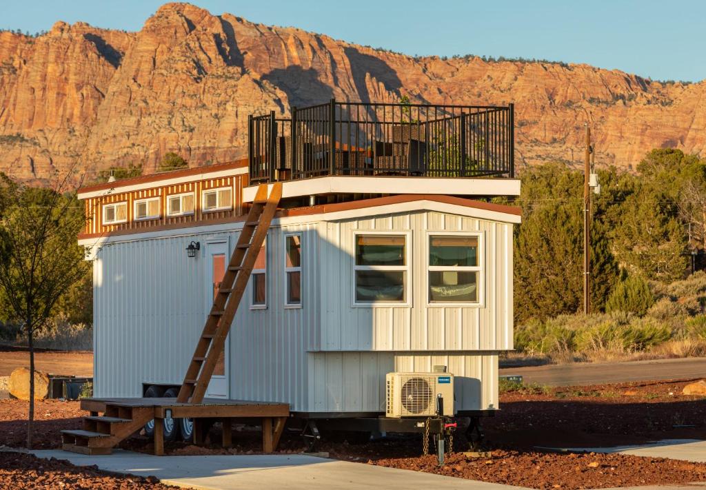 a small house with a ladder in front of a mountain at Aloha Tiny Home in Apple Valley