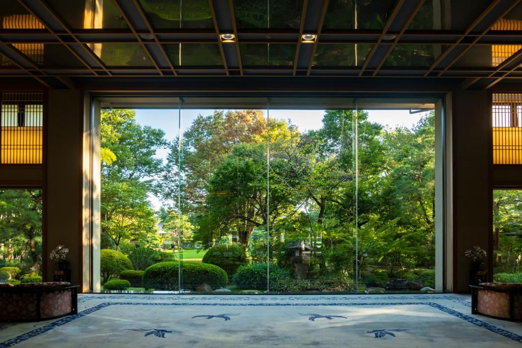 a room with a large window looking out at a garden at Tokiwa Hotel in Kofu