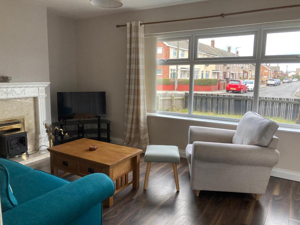 a living room with a blue couch and chairs and a window at Challoner House - sleeps 5 in Hartlepool