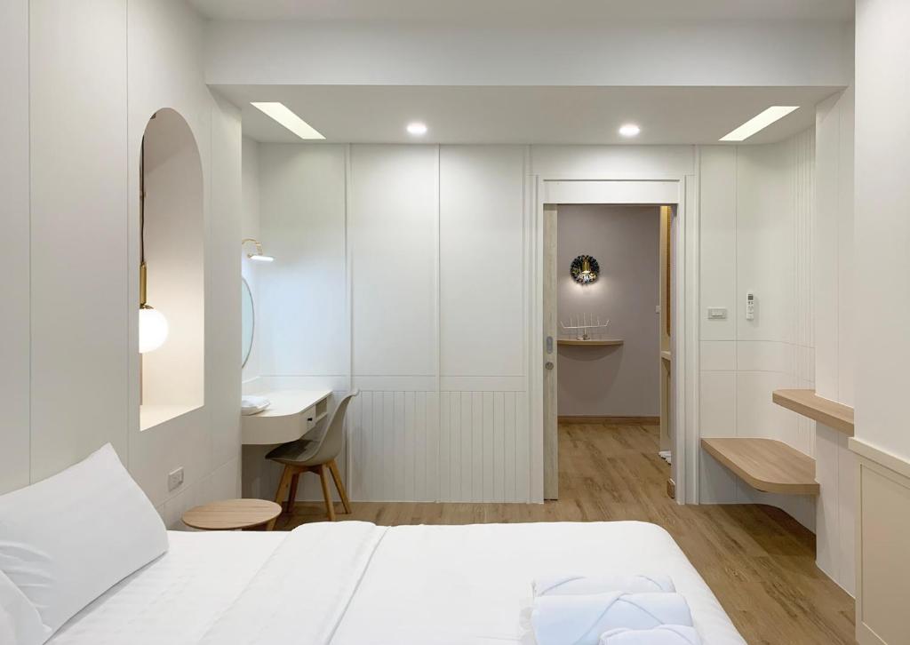 a white bedroom with a bed and a desk at Moon House BKK Room 3A in Bangna