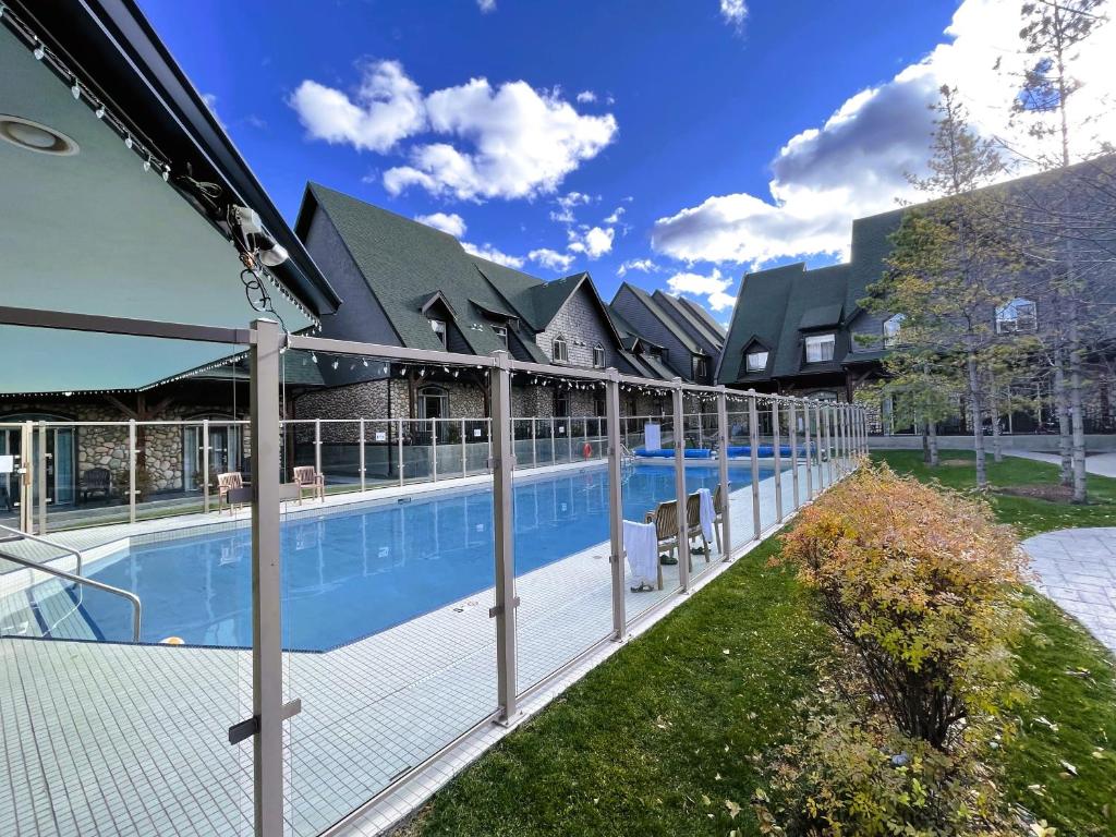 a swimming pool with a fence next to a building at Mountain Chalet at Mystic Springs, 2BR, 2BA, Heated Pool, Hot Tub! in Canmore