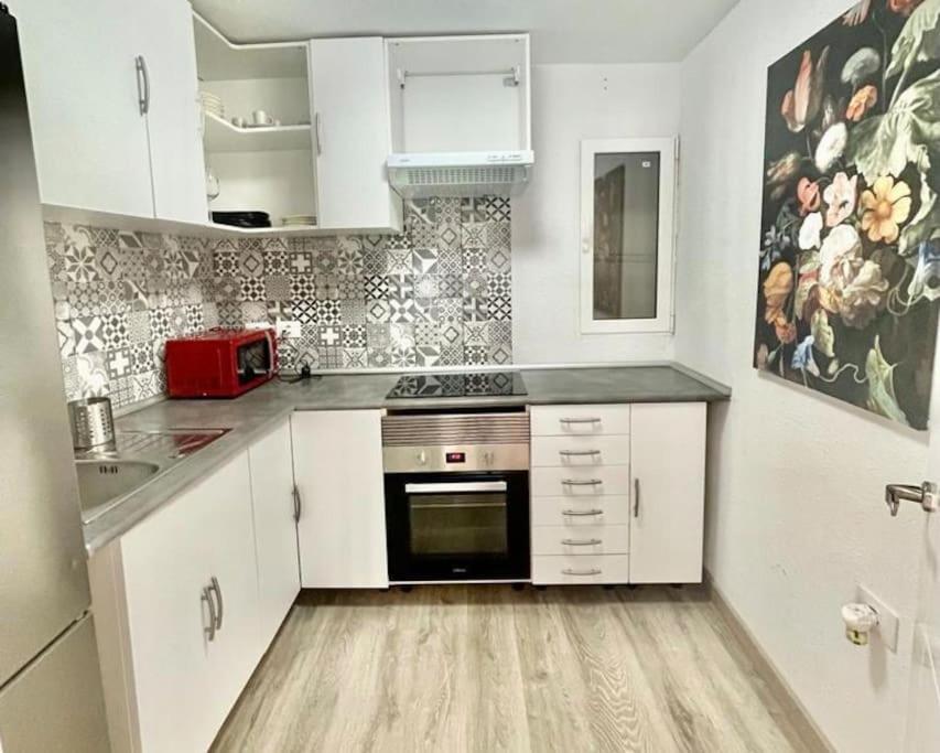 a kitchen with white cabinets and a black oven at 2 Bedrooms Flat 50 mts away from Las Canteras beach in Las Palmas de Gran Canaria