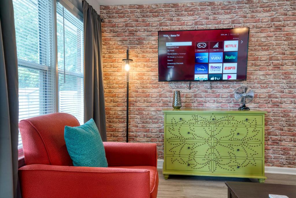 a living room with a tv on a brick wall at Trendy Escape ◉ California King bed awaits! in Charlotte