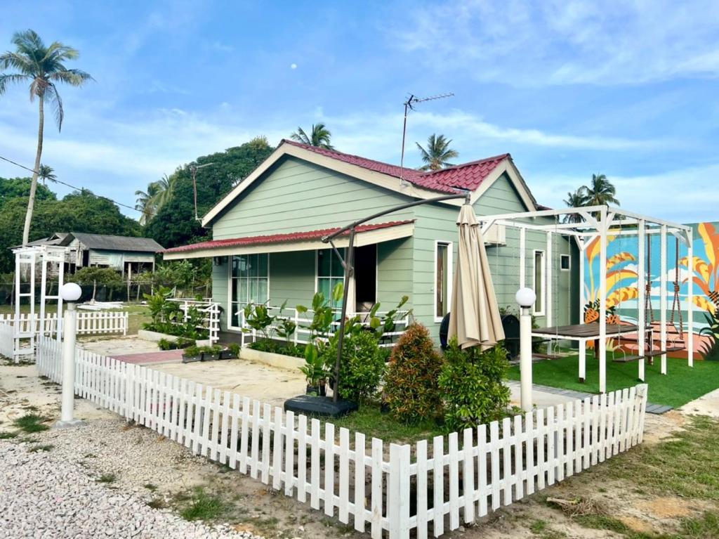 a house with a white picket fence in front of it at Chantara Cottage in Kampung Mawar