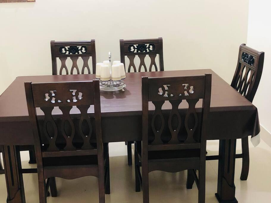 a dining room table with two chairs and a table with candles at Home Away From Home in Chittagong
