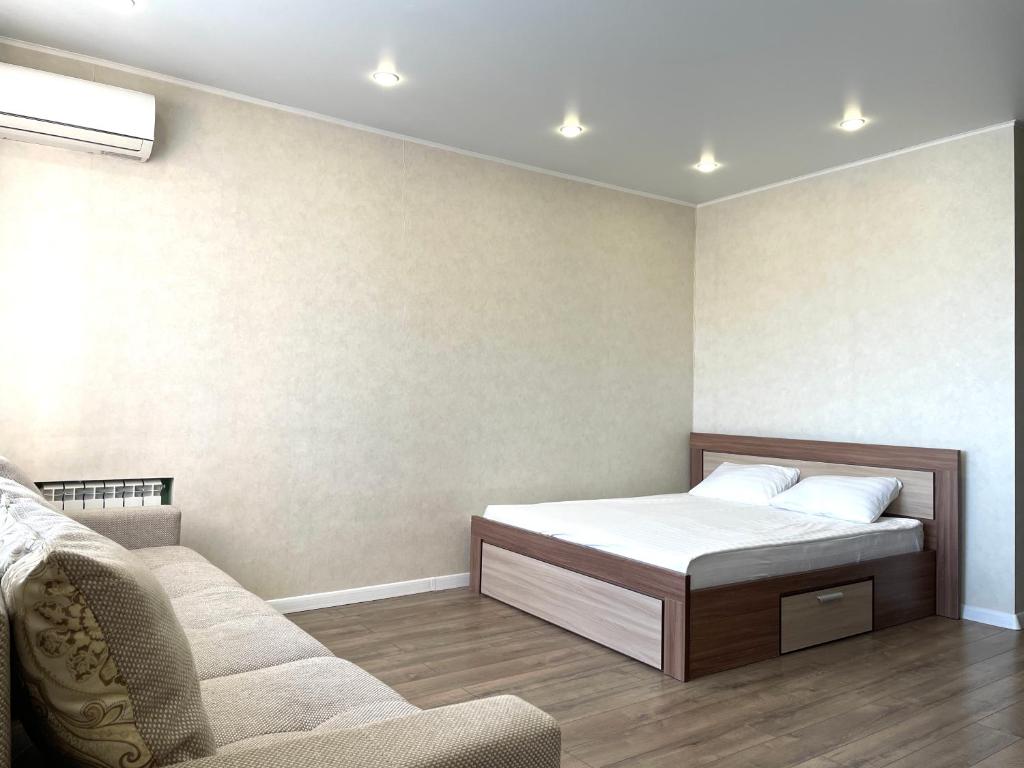 1 dormitorio pequeño con 1 cama y 1 sofá en Новостройка с красивым видом 9 этаж, en Petropavlovsk
