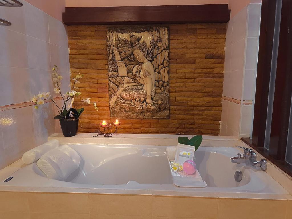 a large white bath tub with a painting above it at Suan Palm Garden View in Rayong