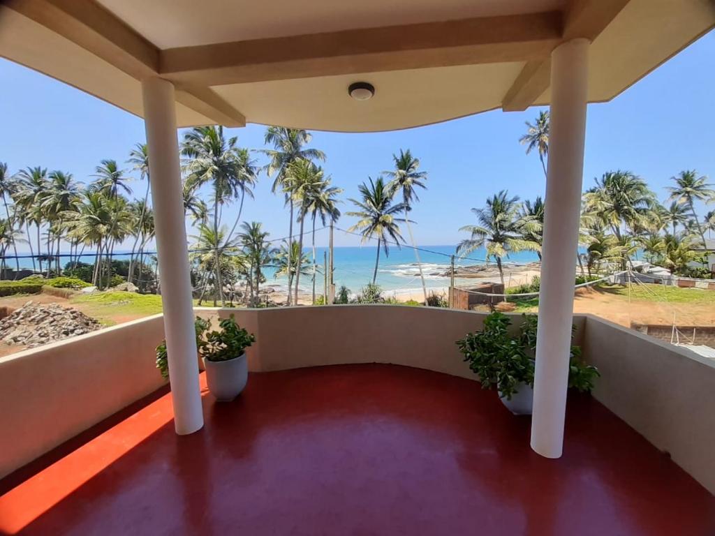 balcón con palmeras y vistas al océano en Dinuli home stay, en Ahungalla