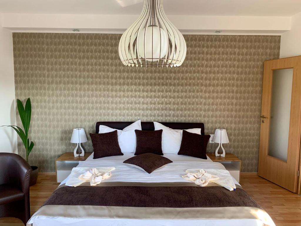 a bedroom with a large bed and a chandelier at Chance Apartman Bükfürdő in Bük