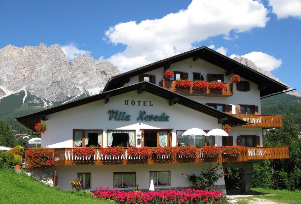 un hotel in montagna con fiori e ombrelloni di Hotel Villa Nevada a Cortina dʼAmpezzo