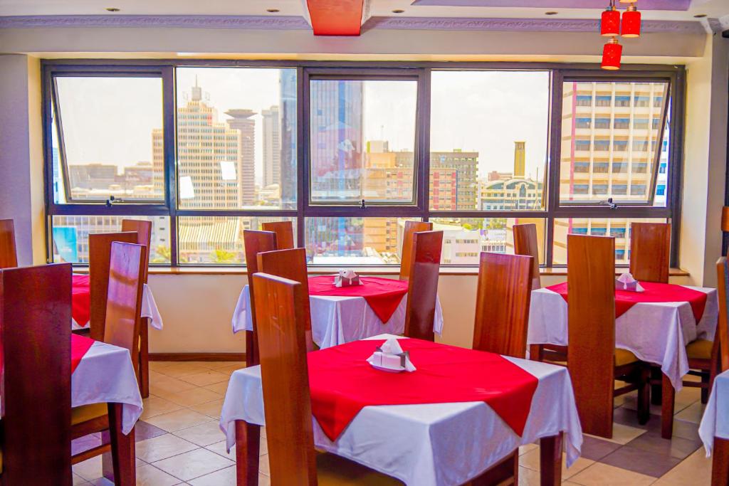 a restaurant with red and white tables and windows at After 40 Hotel in Nairobi