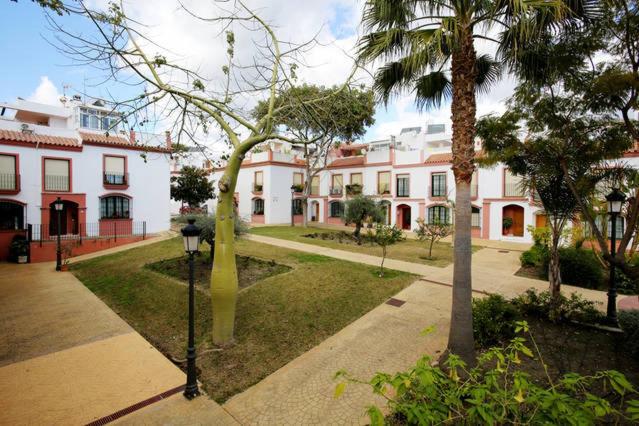 ein Gebäude mit einer Palme inmitten eines Parks in der Unterkunft Hospederia V Centenario in Estepona