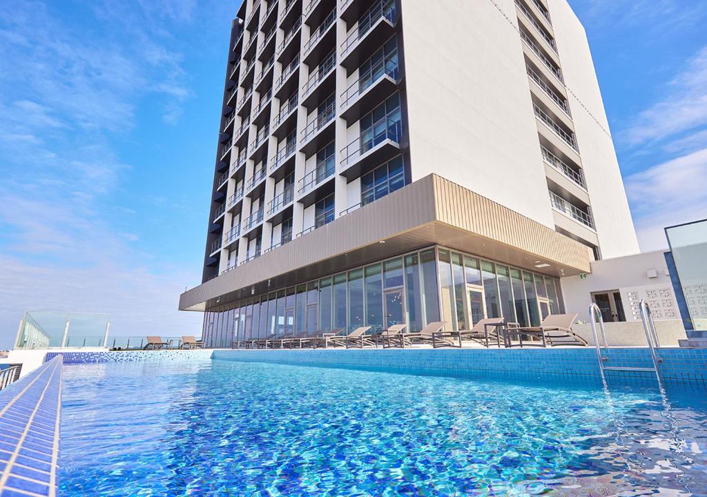 un hotel con piscina frente a un edificio en HOTEL AlaCOOJU OKINAWA en Minatogawa