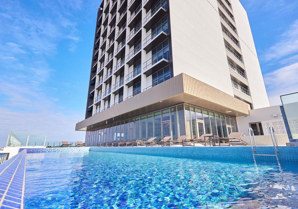 a hotel with a swimming pool in front of a building at HOTEL AlaCOOJU OKINAWA in Minatogawa