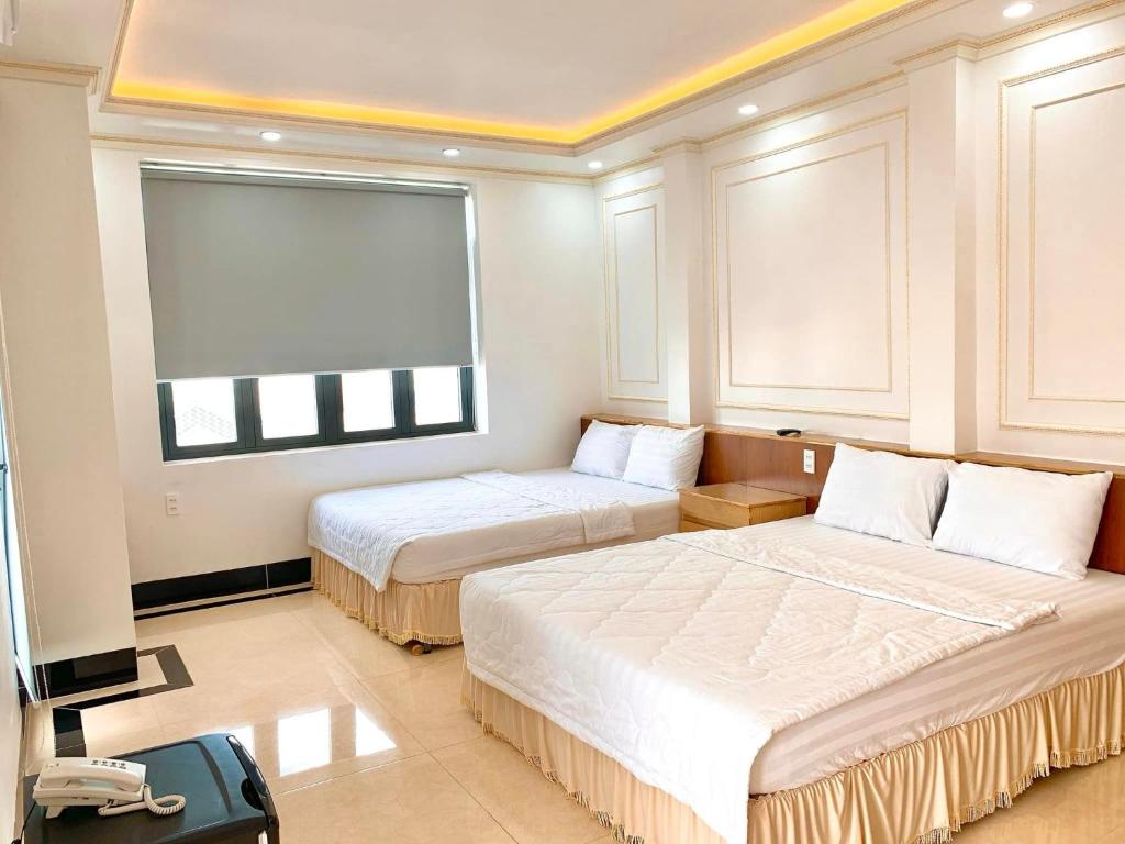 ein Hotelzimmer mit 2 Betten und einem Fenster in der Unterkunft Phụng Hoàng Vũ in Bạc Liêu