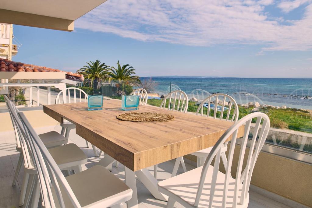 a wooden table and chairs on a balcony with the ocean at Sea Front Zante Apartments in Zakynthos Town