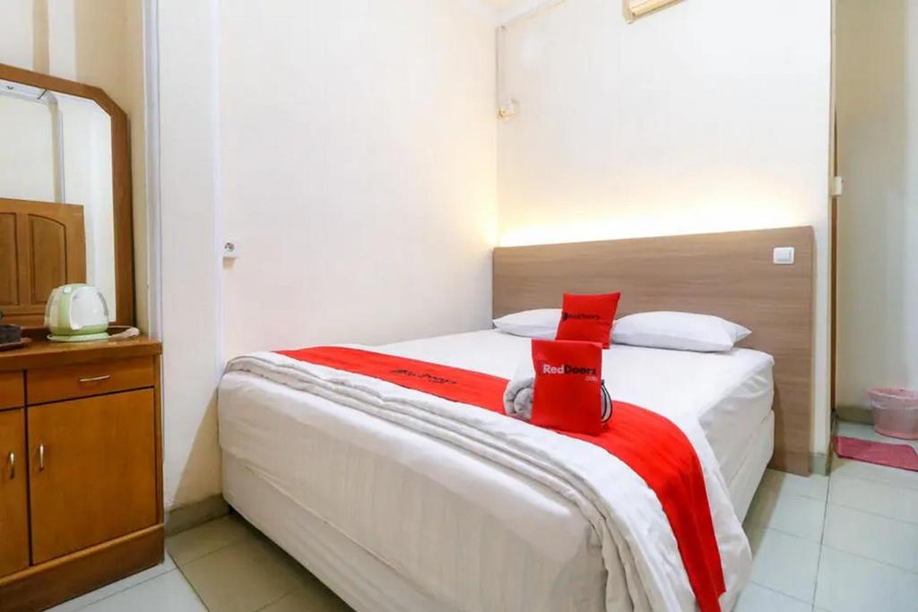 a bedroom with a bed with a red blanket on it at RedDoorz Plus near WTC Batanghari Mall in Tanjungjohor