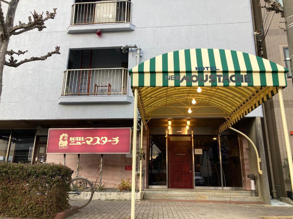 a store front with a green and white awning at Hotel New Moustache in Shizuoka