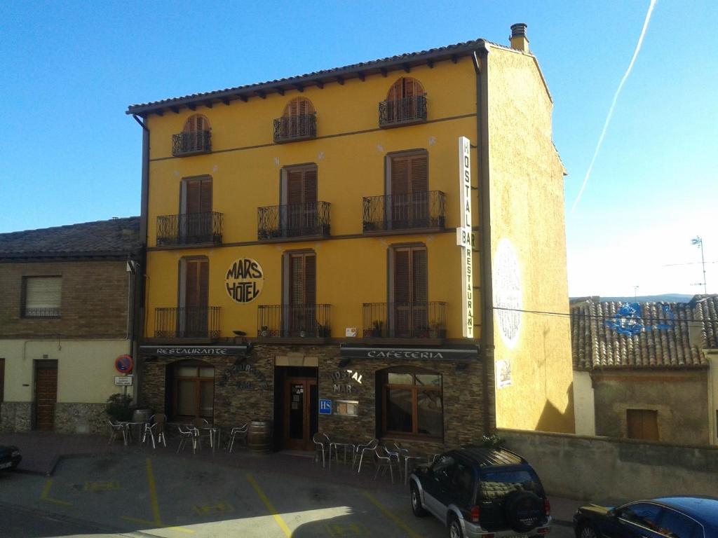 a yellow building with tables and chairs in a parking lot at Hotel Casa Carmen in Benabarre