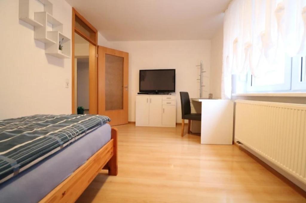 a bedroom with a bed and a flat screen tv at Alb Pension Merklingen in Merklingen