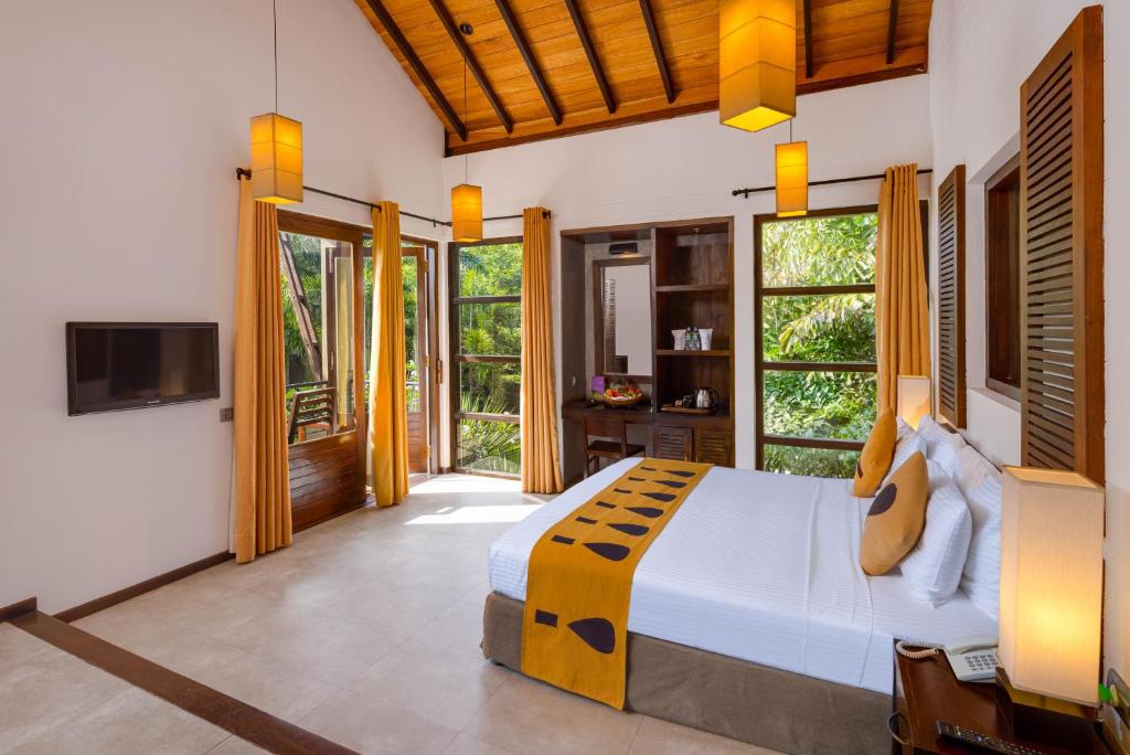 a bedroom with a bed and a tv in a room at Chaarya Resort & Spa in Tissamaharama