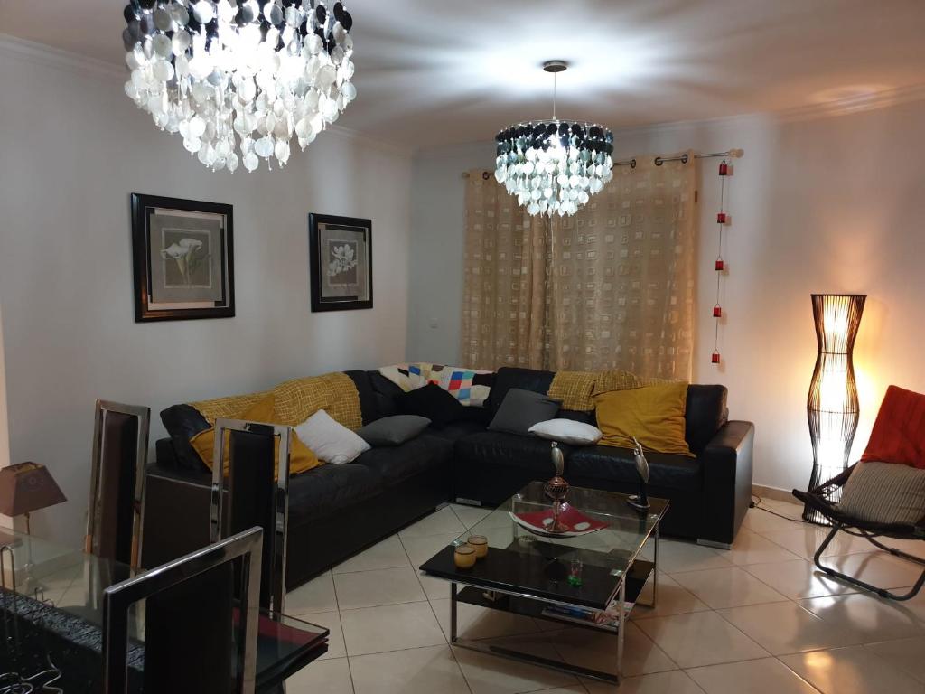 uma sala de estar com um sofá preto e lustres em Splendor Residence Apartment em Portimão