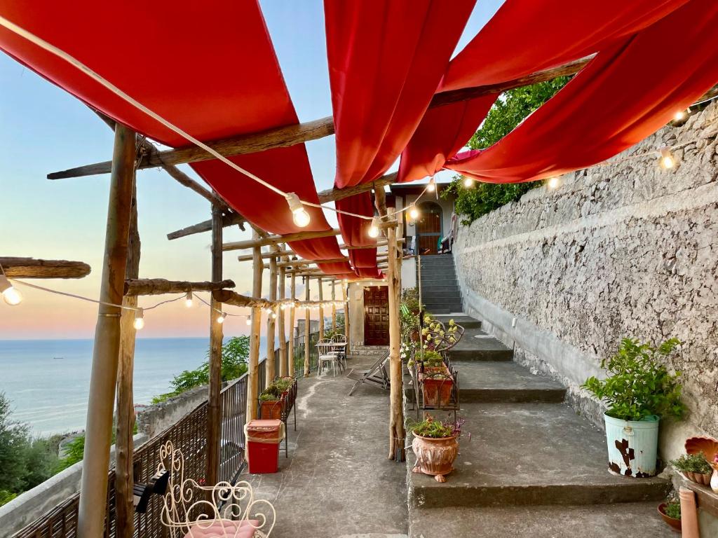 a patio with red umbrellas and the ocean at Casa San Pietro in Amalfi