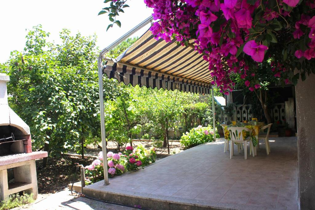 un patio con mesa, sillas y flores en Mille Bouganville, en Platamona