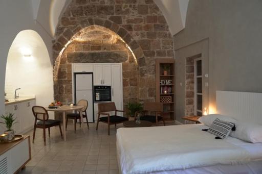a bedroom with a bed and a kitchen and a table at Beit-sitti in ‘Akko