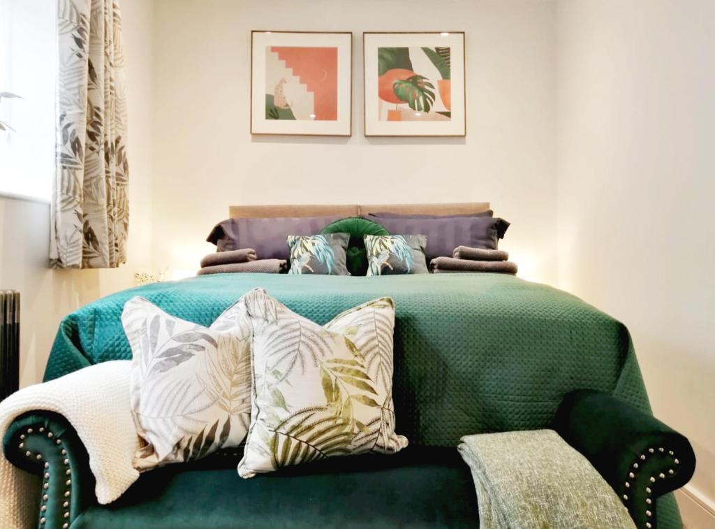1 dormitorio con cama verde y almohadas en Glos Homes Presents - Old Coach House a Quiet Place near Town Centre, en Cheltenham
