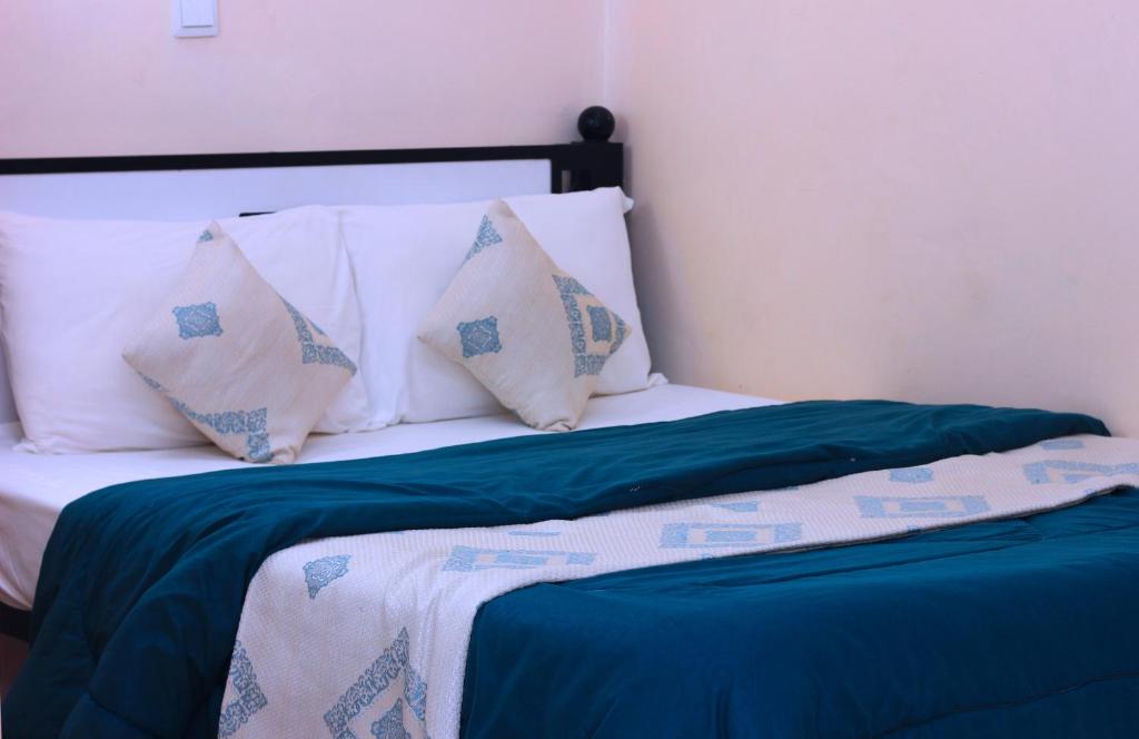 a bed with white and blue sheets and pillows at Eland Accommodations - Ongata Rongai in Ongata Rongai 