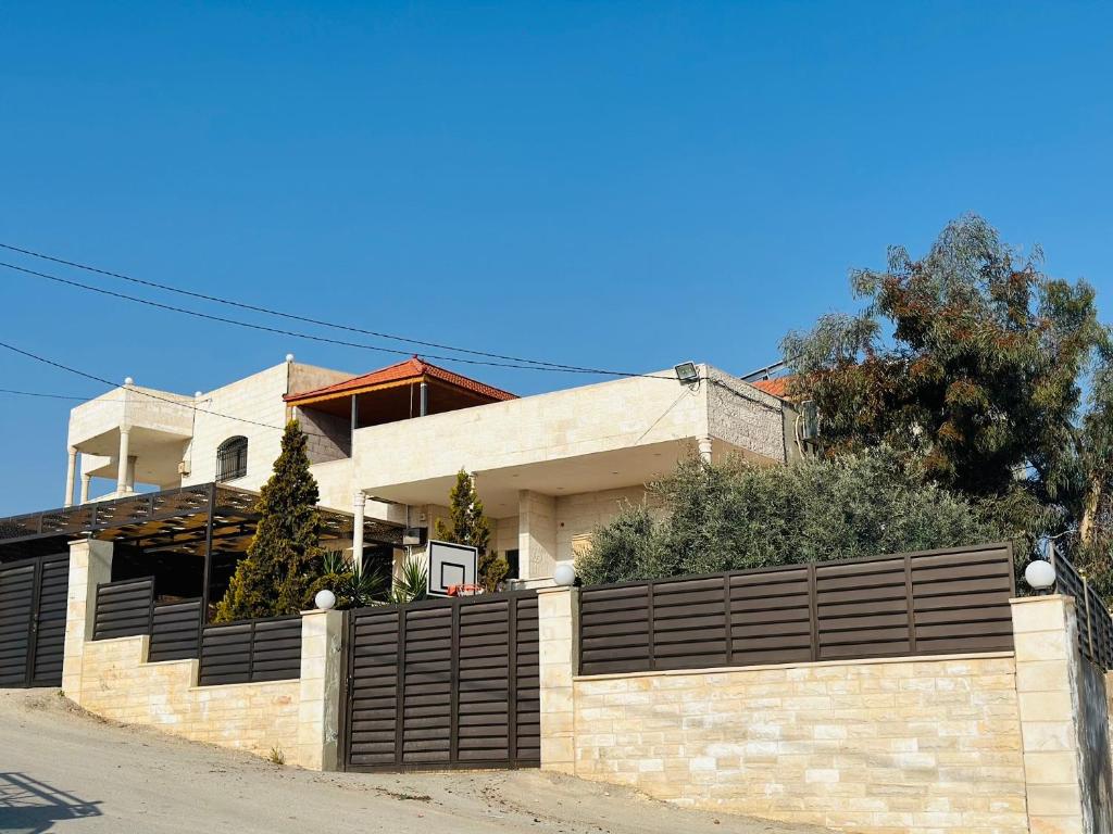 een huis met een stenen muur en een hek bij شقق الياسمين 2 in Jerash