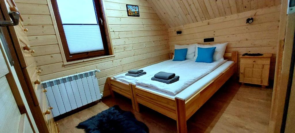 a small bedroom with a bed in a wooden cabin at Sołtysie Chaty - Domek z prywatną balią in Łapsze Niżne