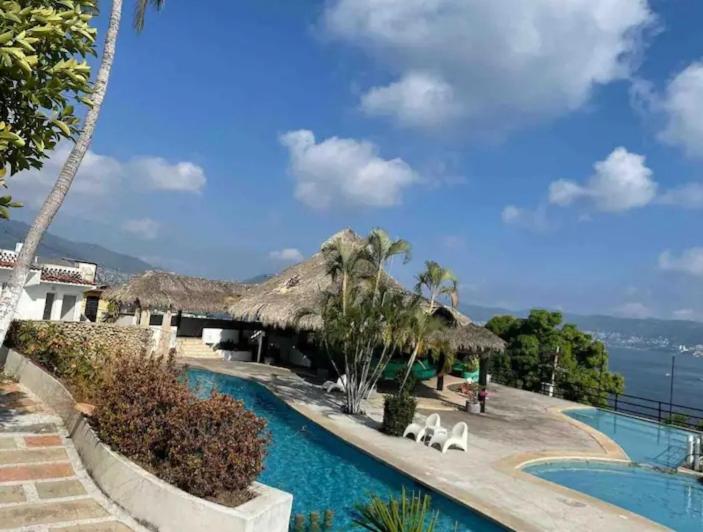 un complexe doté d'une piscine avec deux chaises blanches dans l'établissement Loft 202, à Acapulco