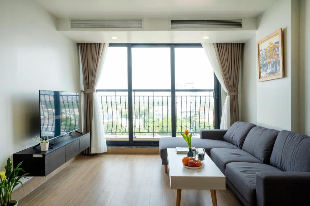 a living room with a blue couch and a large window at SQ Thao Dien in Ho Chi Minh City
