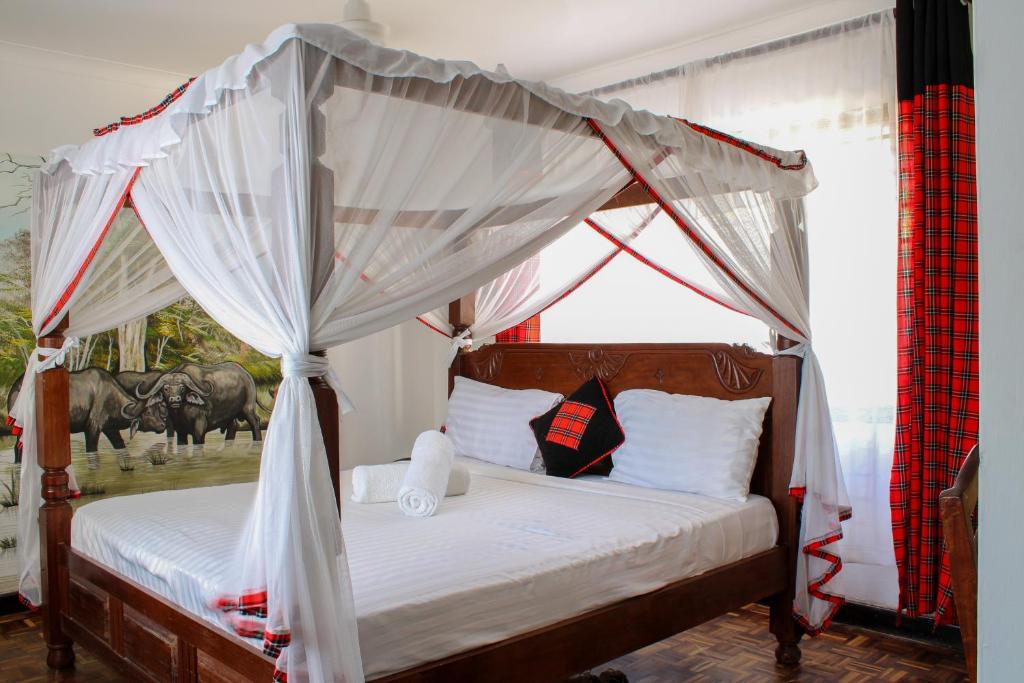 a bedroom with a bed with a canopy with horses in the background at Maasai Villas in Mombasa