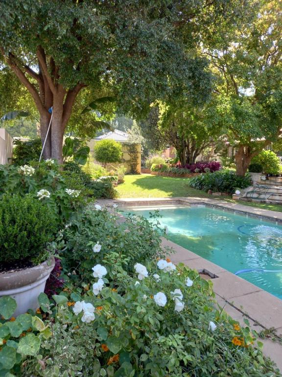 uma piscina num jardim com flores e árvores em Forest Town Guest Cottages em Joanesburgo