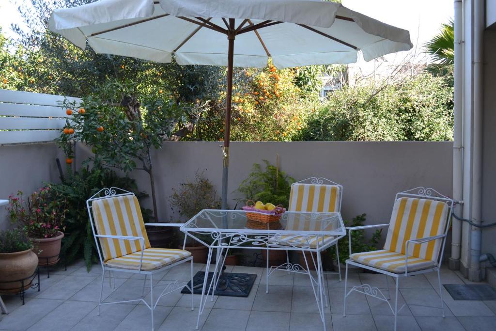 una mesa, sillas y una sombrilla en el patio en Kalamata beach maizonette ground floor and semi-basement with yard, en Kalamata