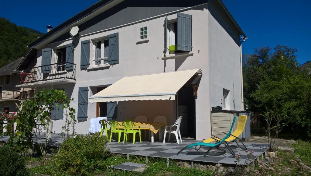 Biały dom z patio z krzesłami i stołami w obiekcie la maison blanche w mieście Ustou