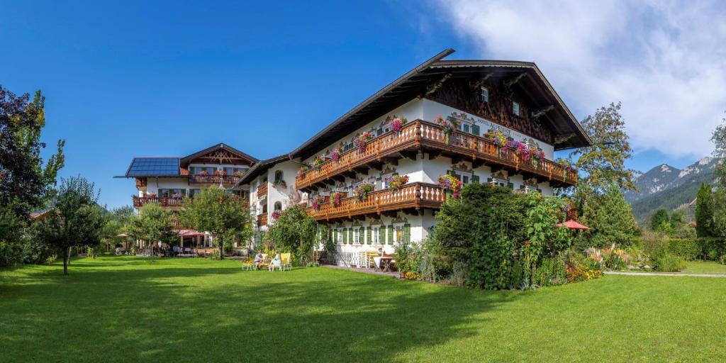 a large building with balconies on a green lawn at Alpenhof Krün in Krün