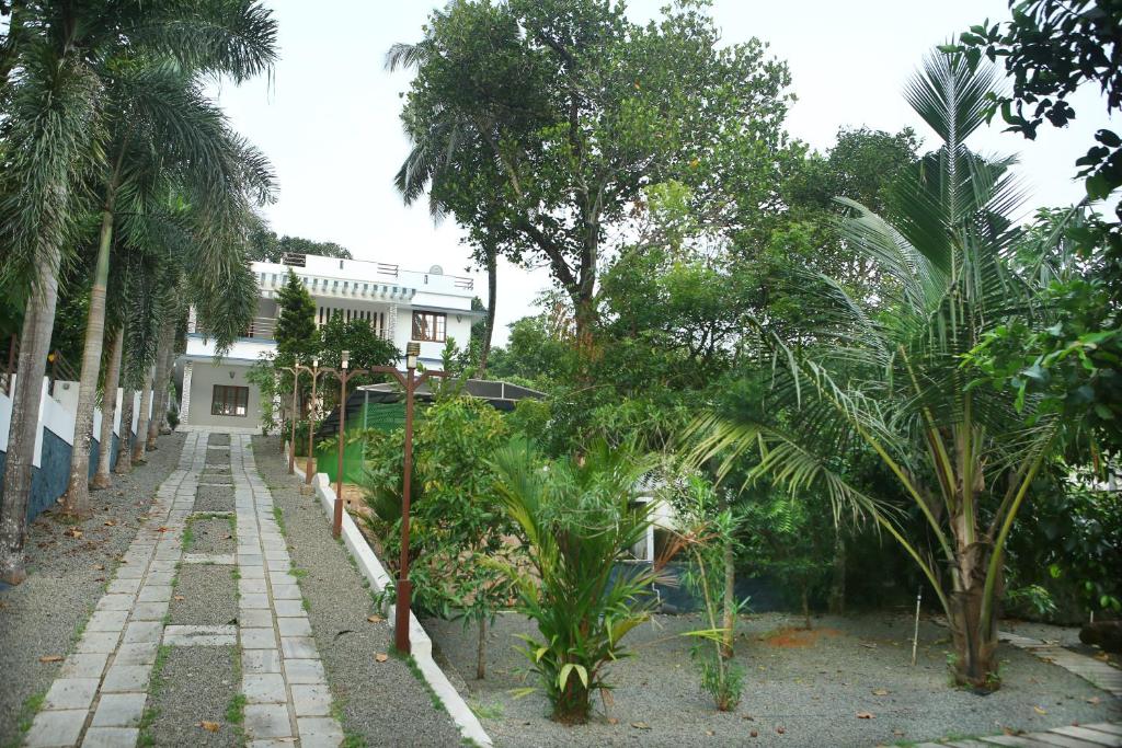 a garden with palm trees and a building at Golden Nest in Rāmamangalam