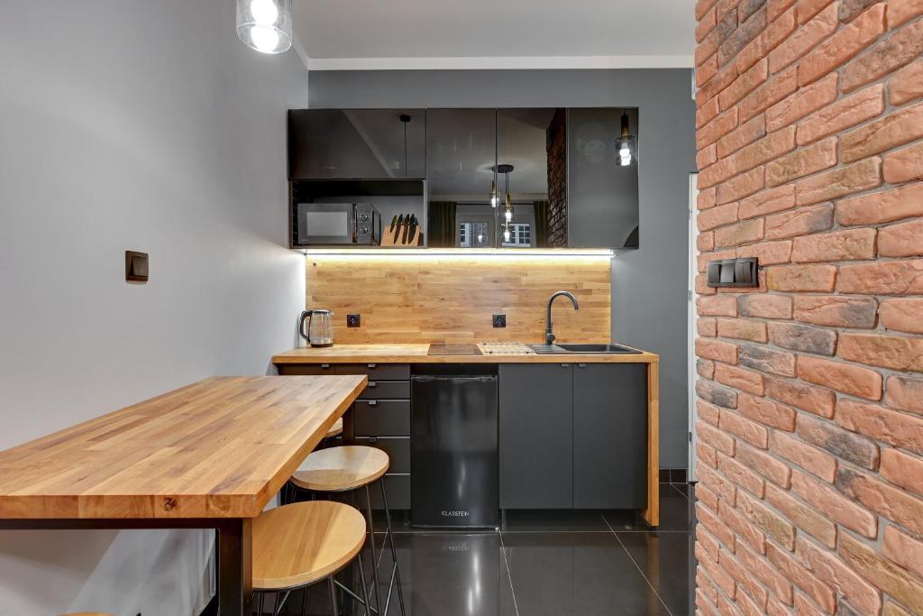 a kitchen with a wooden counter and a brick wall at Apartament Długi Targ in Gdańsk