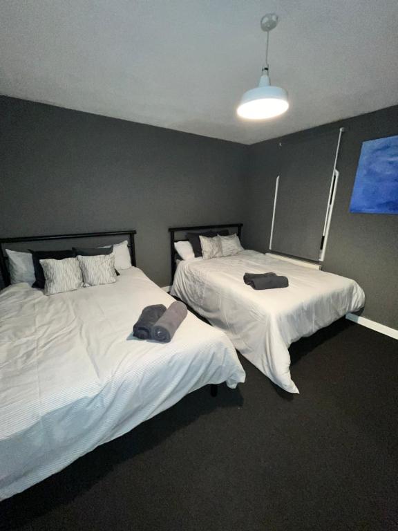 two beds in a room with white sheets at Barbara’s Apartment in London