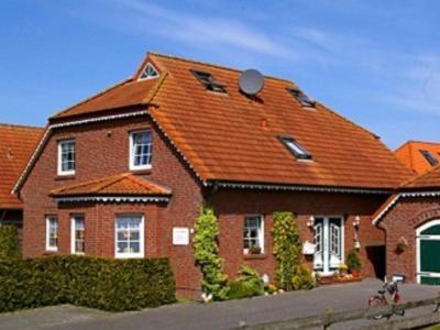 une grande maison en briques avec un toit orange dans l'établissement Kapitänshaus, à Neuharlingersiel