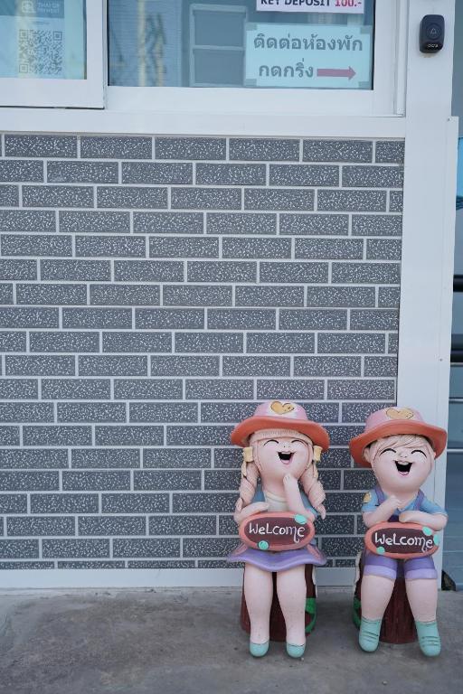 two dolls are standing in front of a brick wall at Baan Sabuy Jung in Aranyaprathet