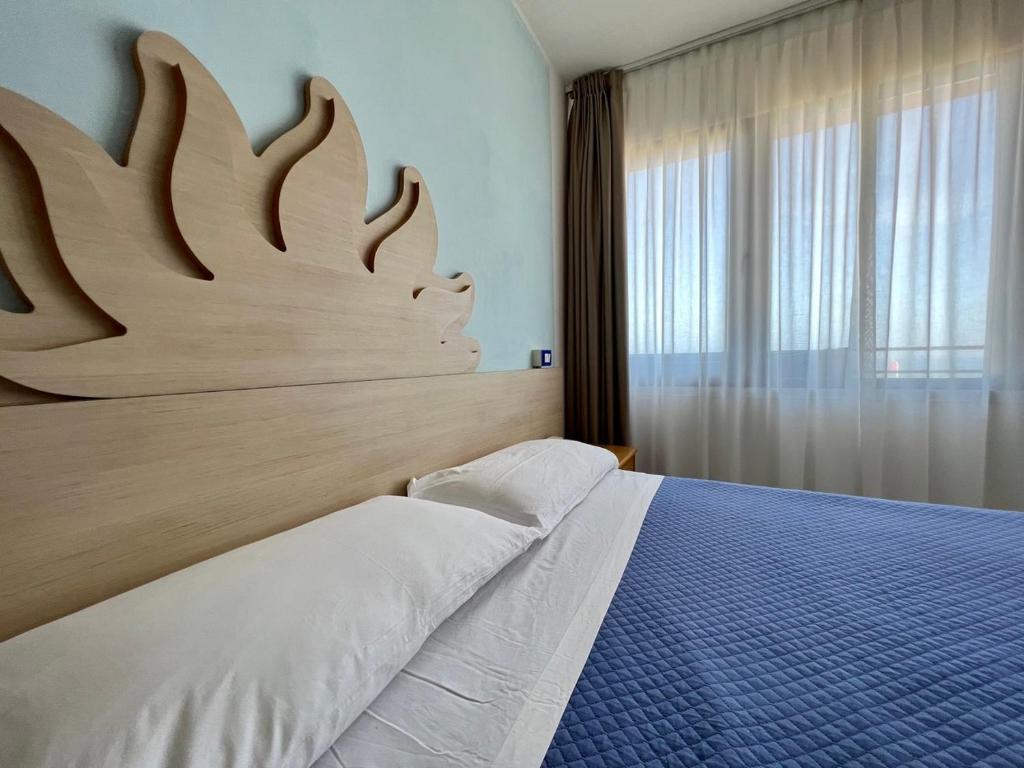 a bedroom with a bed with a large wooden headboard at Hotel Giorgetti Orange in Bellaria-Igea Marina