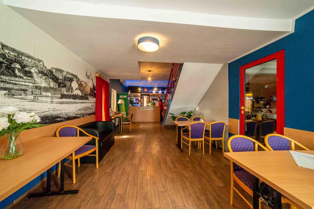 restauracja z drewnianymi stołami i krzesłami oraz niebieskimi ścianami w obiekcie Metropol w mieście Łomża