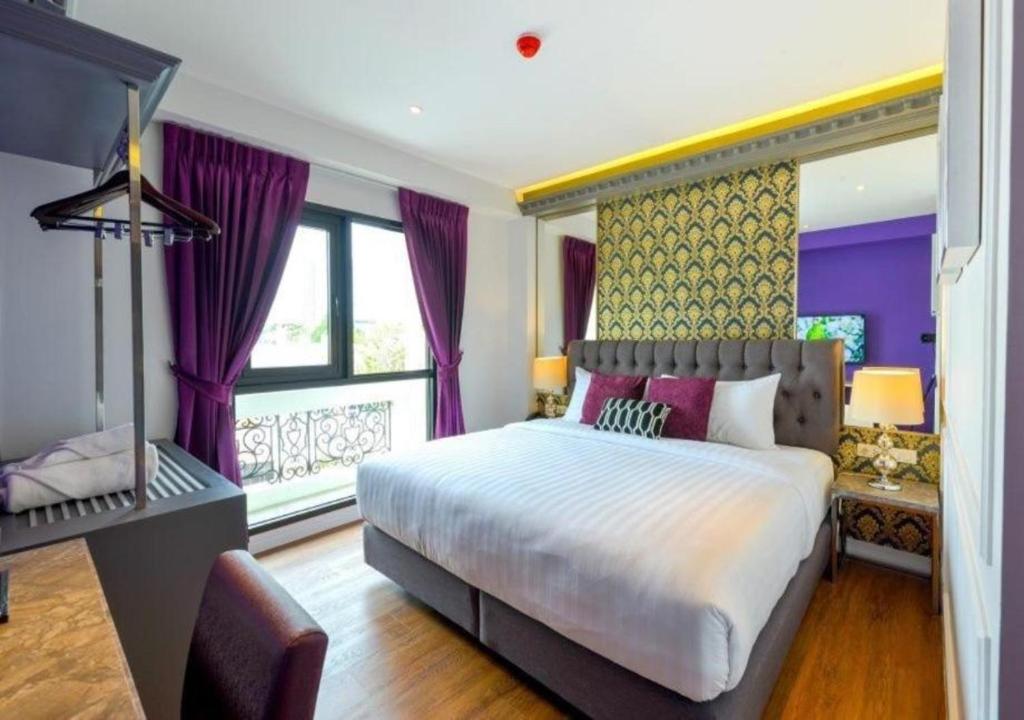a bedroom with a large bed and purple curtains at Villa De Khaosan by Chillax in Bangkok