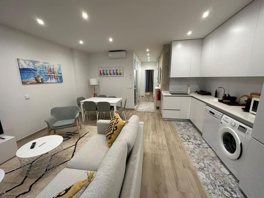 ein Wohnzimmer und eine Küche mit einem Sofa und einem Tisch in der Unterkunft Precioso apartamento con patio. PYP in Valencia