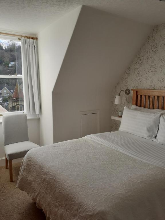 a bedroom with a bed and a chair and a window at Gable Lodge Guest House in Lynton